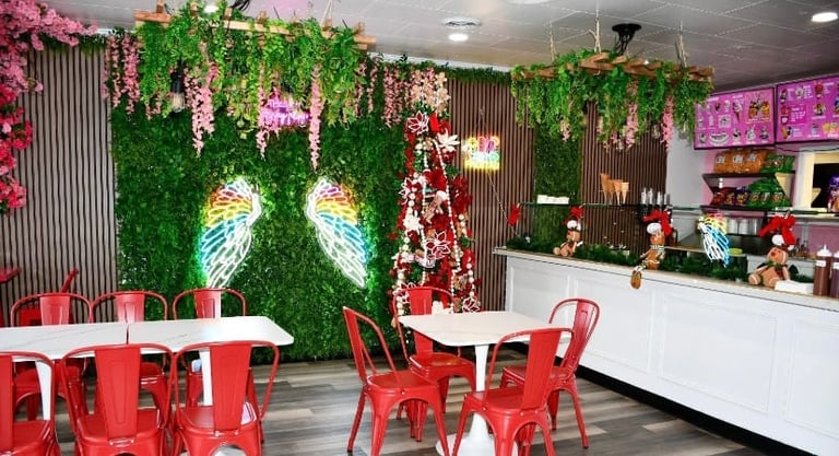 Modern cafe interior with red seating, green living walls, hanging pink flowers, and a counter with holiday decorations