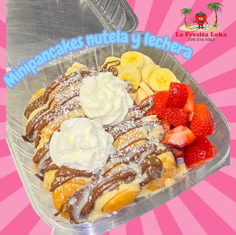 Pancakes with Nutella and condensed milk topped with whipped cream, banana slices, and fresh strawberries in a clear container