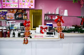 Bright pink retail counter decorated with hanging gingerbread ornaments and red bows